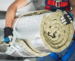 Caucasian Contractor Worker in His 40s with Roll of Mineral Wool Insulation in His Hands Preparing For Commercial Building Walls Insulation.