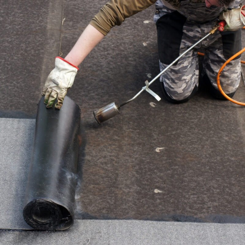 A worker doing roofers welding line with a gas torch